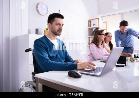 Young Disabled Businessman Sitting On Wheelchair Working In Office Stock Photo