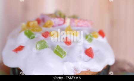 a traditional Easter cake glazed and decorated with marmalade and candied fruits is rotating with colored easter eggs in beautiful glass plate on Stock Photo