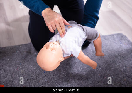 Specialist Giving Baby CPR Dummy First Aid Training To His Colleagues Stock Photo