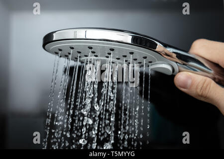 Close-up Of Person's Hand Holding Shower In Bathroom Stock Photo