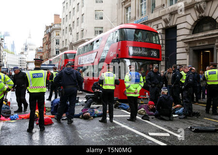 Police officers are seen standing around the environmental activists from Extinction Rebellion Movement Group as they block the Fleet Street during the protest. The eleventh day of the ongoing protest demanding decisive action from the UK Government on the environmental crisis. Stock Photo