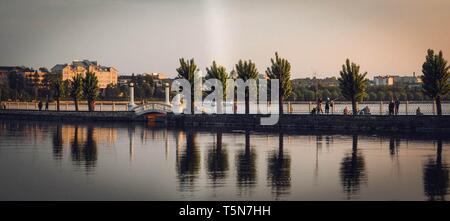 Colorful trees reflecting in lake in the city with bridge Stock Photo
