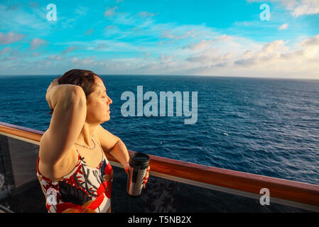 Woman on a cruise ship looks off into the sunset Stock Photo