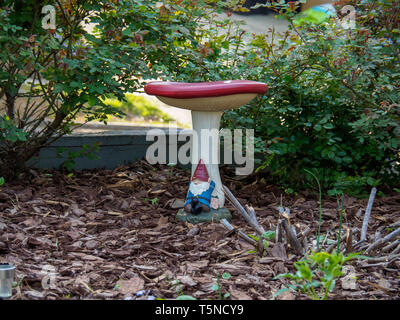 Gnome Sleeping Under a Mushroom in a Garden Stock Photo