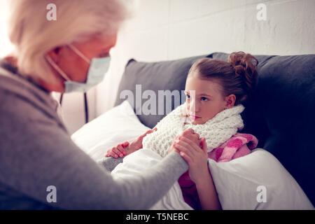 Girl wearing warm beige scarf having flue looking at granny Stock Photo