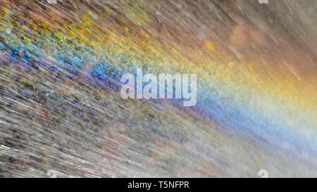 Closeup of a rainbow in a spray of water forming a natural pattern of vibrant colors and white streaks from motion blur droplets. Stock Photo
