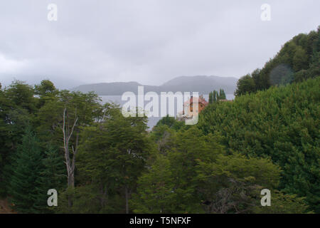A house by a forested cliff with a view to the Nahuel Huapi Lake, in Argentinian Patagonia. Stock Photo