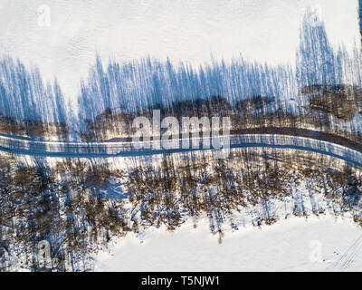 Aerial view of a winter road between two frozen lake. Winter landscape countryside. Aerial photography of snowy forest and frozen lake with road. Capt