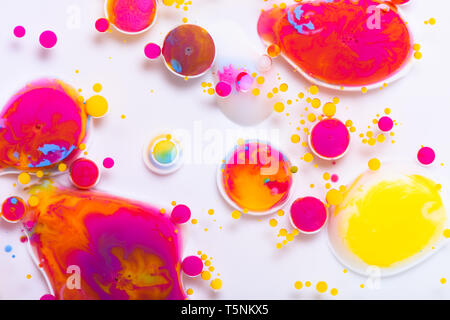 Colorful paint drops mixed in liquid on white background Stock Photo