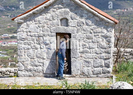 Boy visiting little chapel - Serbian Orthodox Church shrine. Sacral architecture -  Ljesevici / Montenegro. Stock Photo