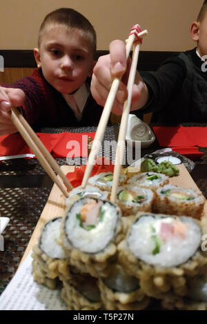 Two brothers eat sushi rolls at home. 2019 Stock Photo