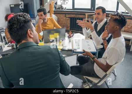 Live communication in a group of young people in the office. Meeting promising businessmen in the office with modern design. Stock Photo