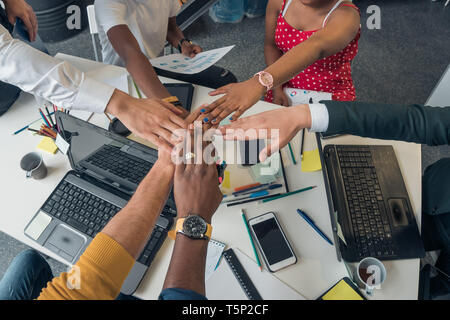 Young people of different nationalities hold a meeting in a modern stylish office. Partners folded his hands in a sign of friendship. Stock Photo