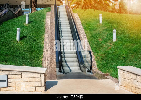 A modern electronic system of many moving on escalator outdoors on a summer day Stock Photo