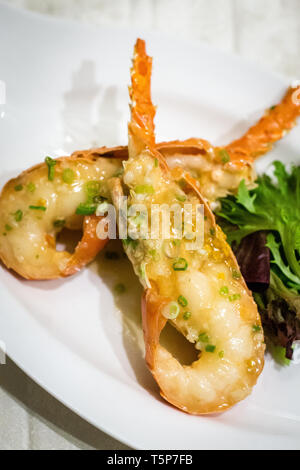 Stir fry Australian lobster with savoury sauce and spring onions and lettuce on the side Stock Photo