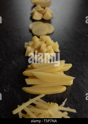 Different cuts of potatoes on a black textured background. Photo taken from above Stock Photo