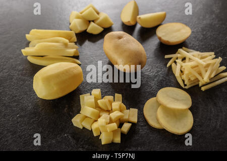 Different cuts of potatoes on a black textured background. Photo taken from above Stock Photo