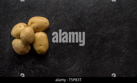 Different cuts of potatoes on a black textured background. Photo taken from above Stock Photo