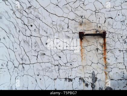 A mottled wall with numerous cracks and a rusty metallic bracket on the surface, forming a "painting" by the force of time. Stock Photo