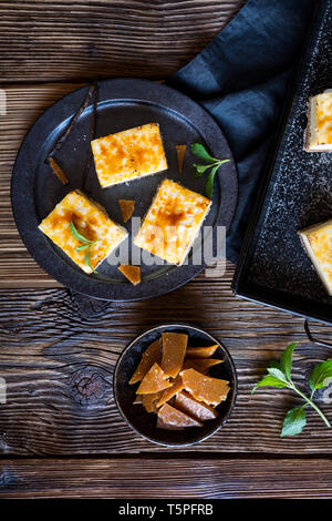 Homemade Creme Brulee cheesecake bars with cream cheese, crushed cookies, topped with caramelized sugar Stock Photo