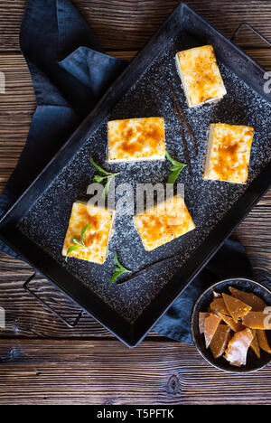 Homemade Creme Brulee cheesecake bars with cream cheese, crushed cookies, topped with caramelized sugar Stock Photo