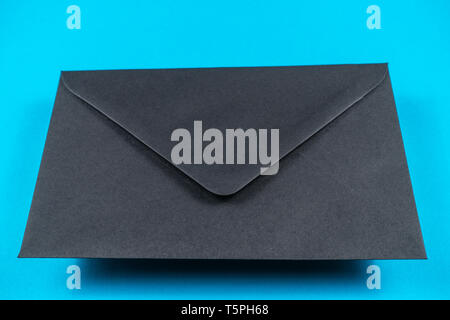Black closed envelope on light blue background. Stock Photo