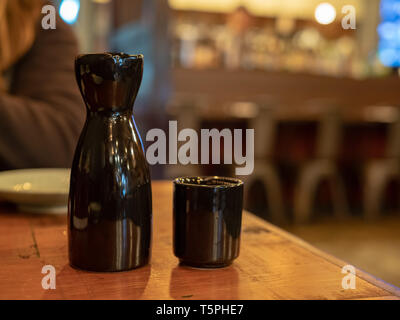 Black sake bottle and glass sitting on table at dining area Stock Photo