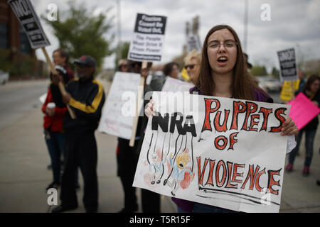 Indianapolis, Indiana, USA. 26th Apr, 2019. A woman holds a sign reading, ''NRA Puppets of Violence.'' as she march to Lucas Oil Stadium to protest against the National Rifle Association and United States President Donald J. Trump who was scheduled to give a speech to gun supporters and the lobbyist group. Credit: Jeremy Hogan/SOPA Images/ZUMA Wire/Alamy Live News Stock Photo