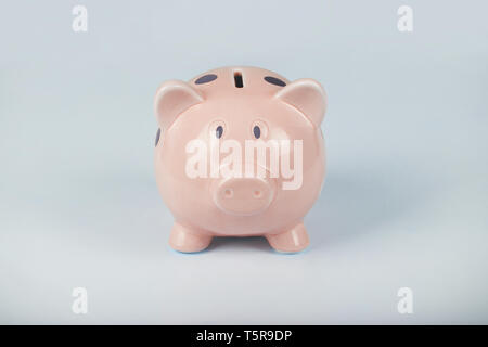 Close up of pink piggy bank with purple dots isolated over blue background with copy space. Finance and money saving concept. Stock Photo