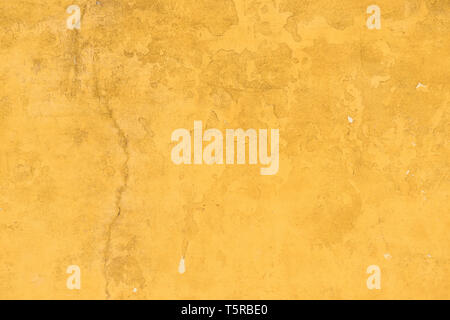 Old concrette wall covered in yellow painted weathered stucco texture background Stock Photo