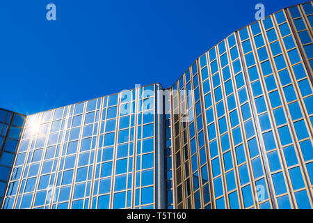 Modern office building with glass facade in front of blue sky Stock Photo