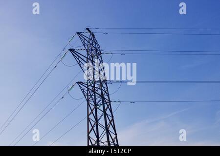 Electricity pylon with power cables against blue sky background - image Stock Photo