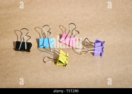 Clips for paper of different colors on the background of rough brown kraft paper. Stationery. With copy space for text. Stock Photo