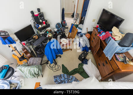 Very messy, cluttered suburban teenage boys bedroom with piles of clothes, music and sports equipment. Stock Photo