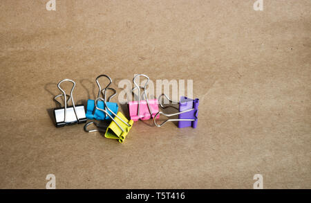 Clips for paper of different colors on the background of rough brown kraft paper. Stationery. With copy space for text. Stock Photo