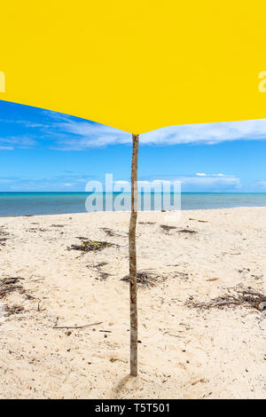 Beautiful beach view from inside yellow tent on sunny summer day. Sea and blue sky in the background. Concept of vacations, peace and relaxation.Bahia Stock Photo