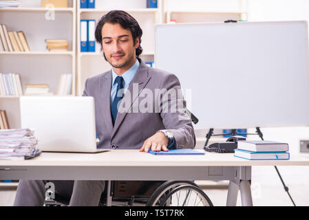 Young handsome employee in wheelchair at the office Stock Photo