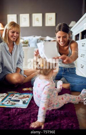 Cheerful young women with small girl having fun indoor Stock Photo