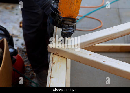 Man building a wooden patio with hammering screwing together beams close up of exterior timber decking. Stock Photo