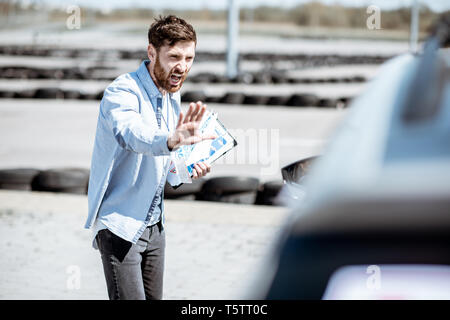 Male instructor showing stop with hands while teaching to park a car on the training ground at the school Stock Photo