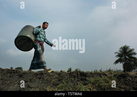 A fisherman walks home along the banks of the Rupsha River in Khulna, Bangladesh, after a day spent catching fish. Stock Photo