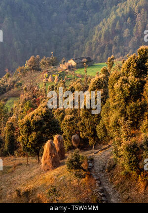 Idyllic rural scene with farmhouse haystacks and wooded mountain slopes in the Himalayan foothills at Gonap in Uttarakhand Binsar area Northern India Stock Photo