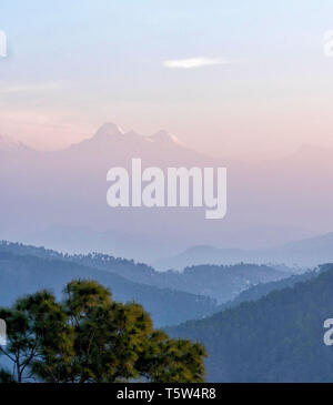 Dawn mist shrouding the distant twin peaks of Nanda Devi the second highest mountain in the Indian Himalayas - from Binsar foothills in Uttarakhand