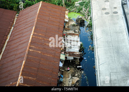 slum zone, photo shooting from top view, can see rust rooftop, garbage and dirty water beside building. Stock Photo