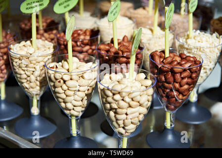 Different peanuts nuts in glass goblets on display in a store Stock Photo
