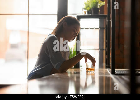 Young sad woman sitting on bar counter drinking alcohol drinks Stock Photo