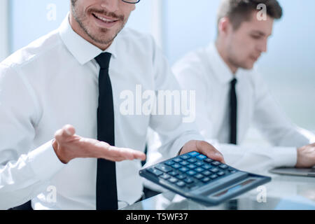 businessmans hand working with finances about cost.calculator and loptop on the glass table in modern office in morning light Stock Photo