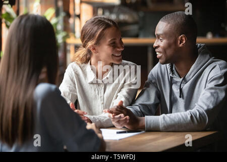 Diverse happy couple sitting at table with real estate agent Stock Photo