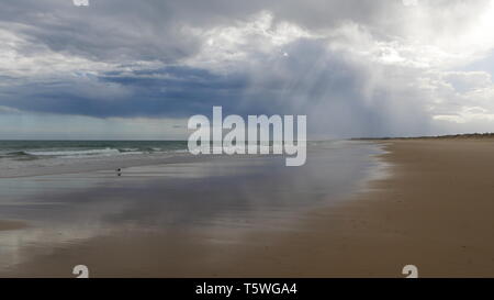 Sun, clouds and gusty wind on the beach of Praia Verde Stock Photo