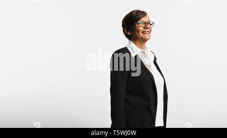 Cheerful senior woman isolated on white background looking away. Side view of smiling senior woman in formal business attire. Stock Photo